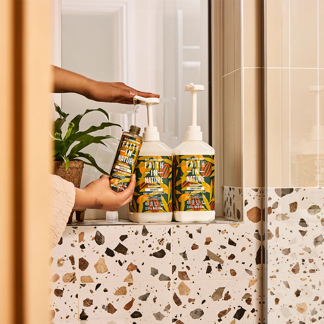 Person holding a bottle of 'Faith in Nature' product in a bathroom setting.