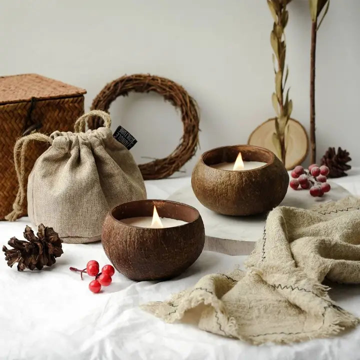 Coconut candles in wooden holders with decorative elements on a white surface