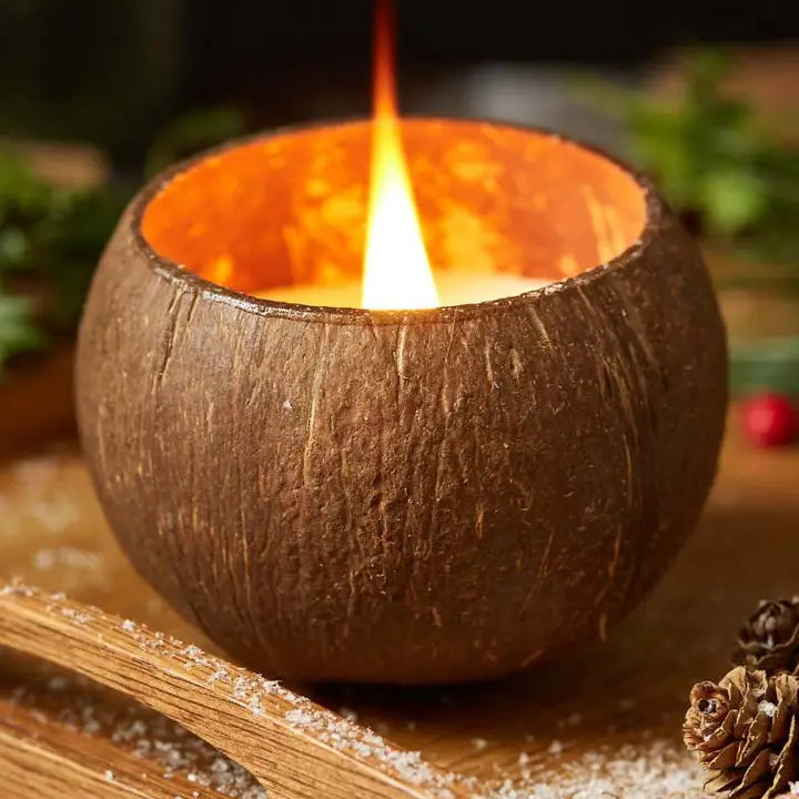 Candle in a coconut shell on a wooden surface with a blurred natural background