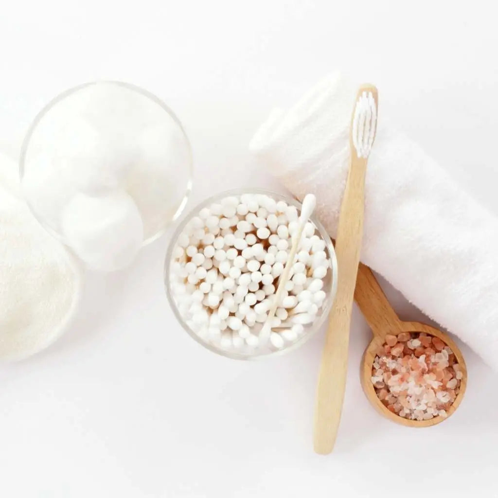 Bowl of toothpicks, wooden spoon with salt, and white cups on a white surface